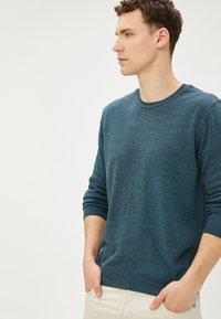Dunkelblauer Pullover mit Rundhalsausschnitt und gerippten Bündchen, aus einem weichen Material gefertigt. Bietet eine lockere Passform und minimalistisches Design.