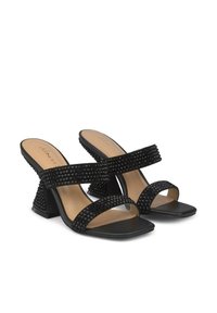 Zwarte mules met hoge hakken, voorzien van gestikte banden met textuur, een gevoerd voetbed en een chunky blokhak. Het vierkante te ontwerp verhoogt de stabiliteit en stijl.