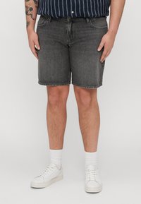 Črne jeans kratke hlače s ravnim krojem, ki imajo pet žepov in surov rob. Ustrezajo z belimi supergami in prugasto mornarsko srajco.