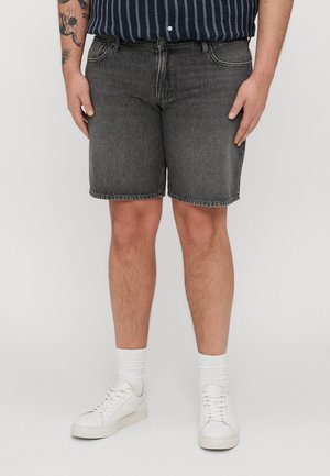 Sorte denimshorts med rett kutt, med fem lommer og råkant. Bært med hvite sneakers og stripete marineblå skjorte.