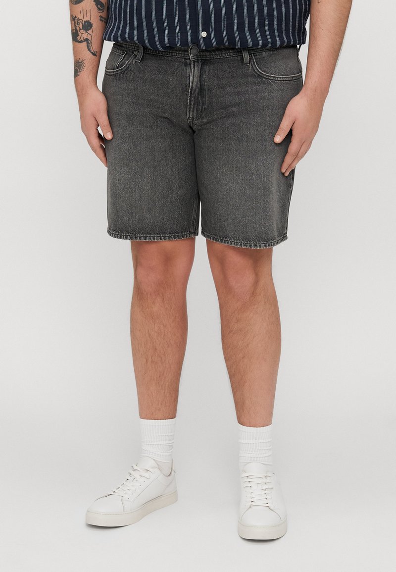 Črne jeans kratke hlače s ravnim krojem, ki imajo pet žepov in surov rob. Ustrezajo z belimi supergami in prugasto mornarsko srajco.