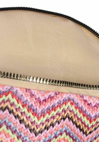 Reißverschlusstasche aus mehrfarbigem gewebtem Stoff mit Chevron-Muster. Das Innere hat ein glattes beiges Futter. Schwarzer Reißverschluss.