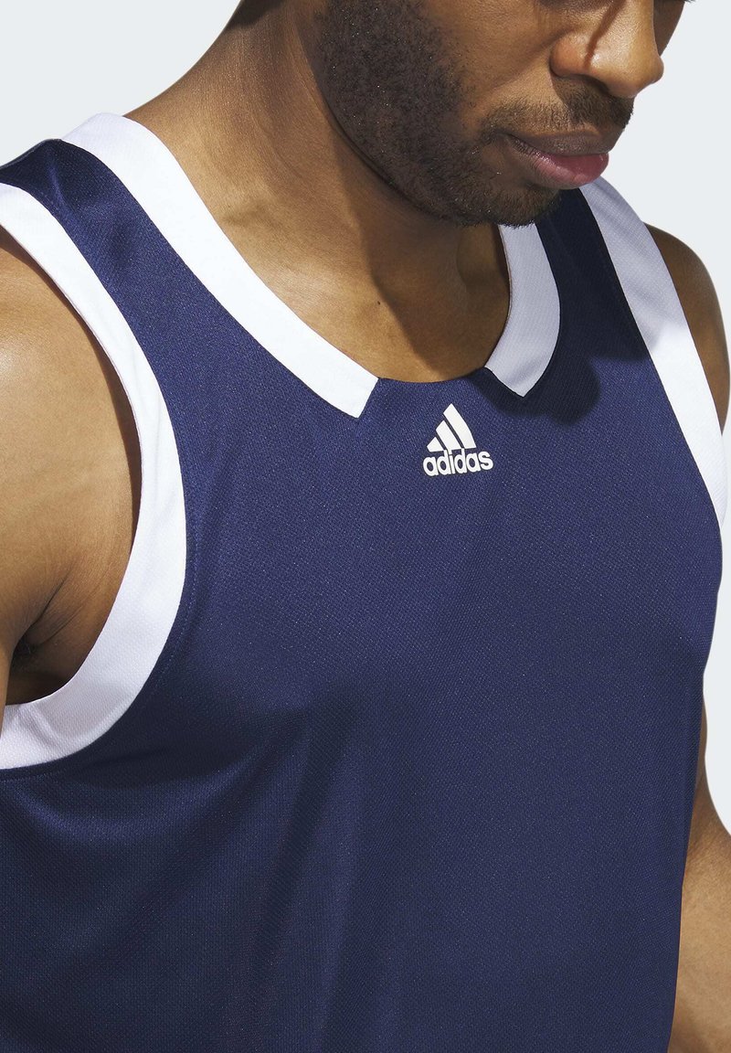 Top deportivo atlético azul con detalles en blanco; cuenta con un escote redondo y textura de malla. Logotipo de Adidas situado en la zona del pecho.