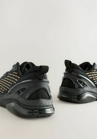Schwarze Athleticsneaker mit strukturiertem Finish, ausgestattet mit atmungsaktivem Mesh und reflektierenden goldenen Akzenten. Gebogene Sohle und Fersensupport-Design.