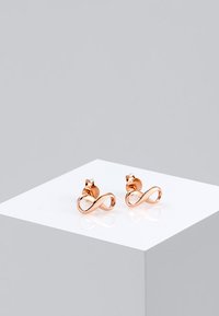 Rosaguld øreringe i stud-stil med et uendelighedssymbol-design, poleret finish og en lille accent øverst.