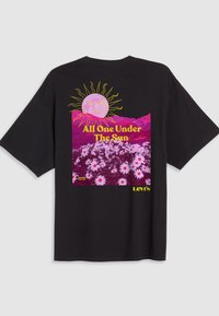 Black cotton t-shirt featuring a vibrant graphic design with a sun, mountains, and a floral pattern in pink and white, with text accents.