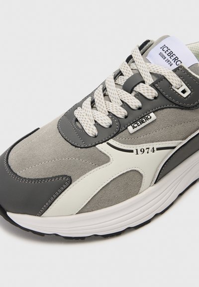 Sneaker grigie realizzate in una combinazione di materiali scamosciati e in pelle, con lacci texturizzati, una suola intermedia bianca e un dettaglio di branding "1974".