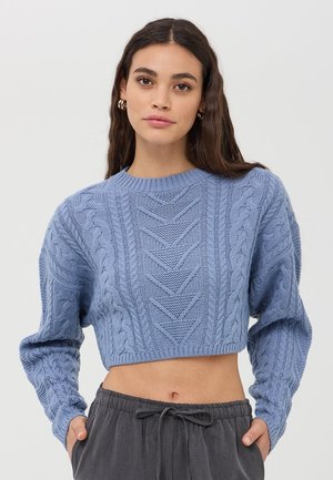 Maglione blu a maglia ritagliato con motivi a trecce, scollatura rotonda a coste e maniche lunghe svasate, abbinato a pantaloni grigi con coulisse.