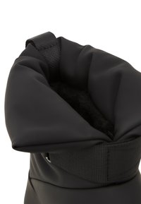 Botas negras impermeables con un suave forro interior, que cuentan con una parte superior plegable y una correa texturizada para un cierre seguro. Acabado exterior liso.