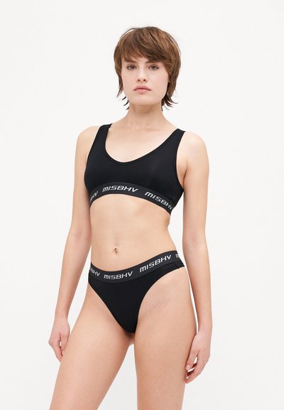 Soutien-gorge de sport noir et culotte assortie en tissu lisse, avec une large bande élastique affichant le nom de la marque "MISBHV" en gris.