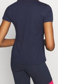 Marinblå kortärmad t-shirt med rund halsringning. Tillverkad av mjukt bomullstyg, har en figursydd design och en något rundad fåll.