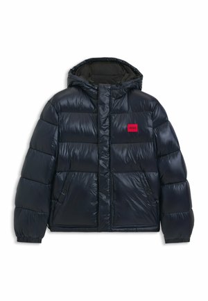 Puffer-takki tummansinisellä sävyllä, jossa on kiiltävä pinta. Takissa on huppu, edessä vetoketjusuljenta, kaksi sivutaskua ja punainen brändipatch.