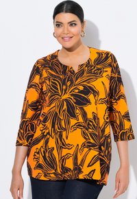 Orange Bluse mit schwarzem Blumenmuster, V-Ausschnitt, drei ViertelÄrmel und lockerer Passform. Der Stoff wirkt glatt mit einer weichen Textur.