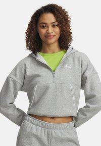 Šedá mikina s kapucňou na zips a prednou vreckom, vyrobená z jemného materiálu, v kombinácii so svetlozeleným priliehavým topom. Obsahuje biele akcenty.