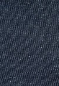 Tmavomodrá džínovina s diagonálnym ryžovaným vzorom a jemnými bielymi škvrnkami po celom materiáli.