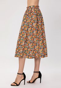 Jupe midi florale avec un fond noir, ornée de fleurs orange, roses et vertes. Taille élastique et design plissé.