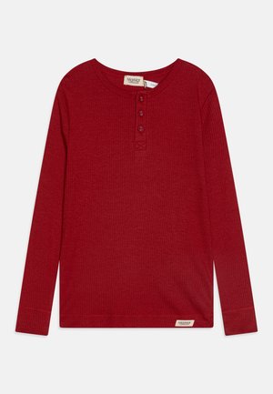 Camisa henley de manga longa vermelha feita de tecido canelado, com gola redonda e punho de três botões. Pequeno rótulo da marca na bainha.