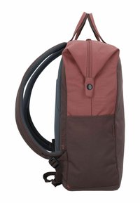 Mochila con una sección superior color marrón oscuro y una sección inferior marrón oscuro. Presenta correas acolchadas, un cierre de botón y un bolsillo lateral. Tejido texturizado.