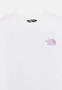Biała koszulka z okrągłym dekoltem, z małym różowym logo "The North Face Yosemite, CA" na górnej lewej stronie klatki piersiowej, oznaczona jako rozmiar dla dziewczynek 4-5 lat.