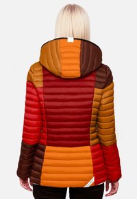 Quilted puffer jacket with a hood, featuring bold colors: red, orange, brown, and yellow in blocks. Includes a side tag detail.