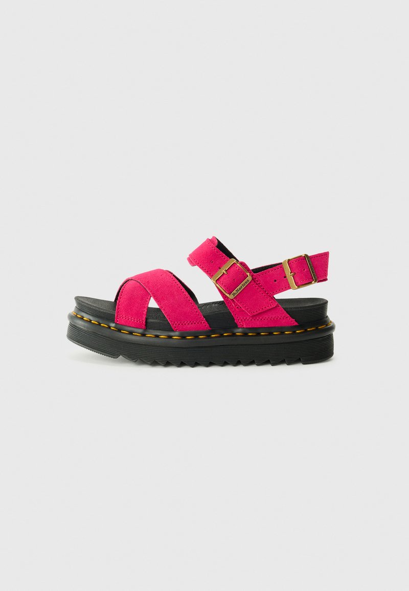 Pink suede sandal with two wide straps over the foot, adjustable buckle, and a thick black rubber sole with a ridged texture and yellow stitching.