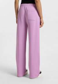 Ljust lila vida sweatpants i mjukt tyg, med resårmidja och en bakficka med broderad märkning.