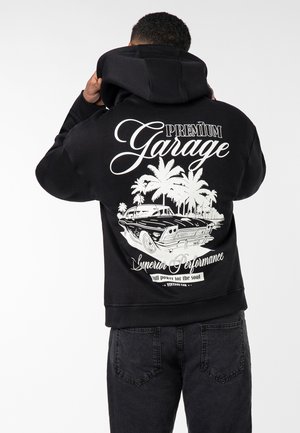 Black hoodie with large white graphic on the back featuring a vintage car, palm trees, and text: "PREMIUM Garage" and "Superior Performance."