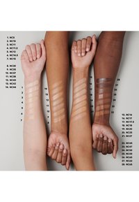 Swatched arms in various skin tones displaying 28 shades of foundation, labeled with corresponding color codes, on a neutral background.