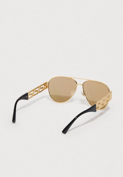 Óculos de sol aviador dourados com lentes castanhas, detalhes decorativos dourados nas hastes e ponteiras pretas brilhantes. Design com armação metálica leve.