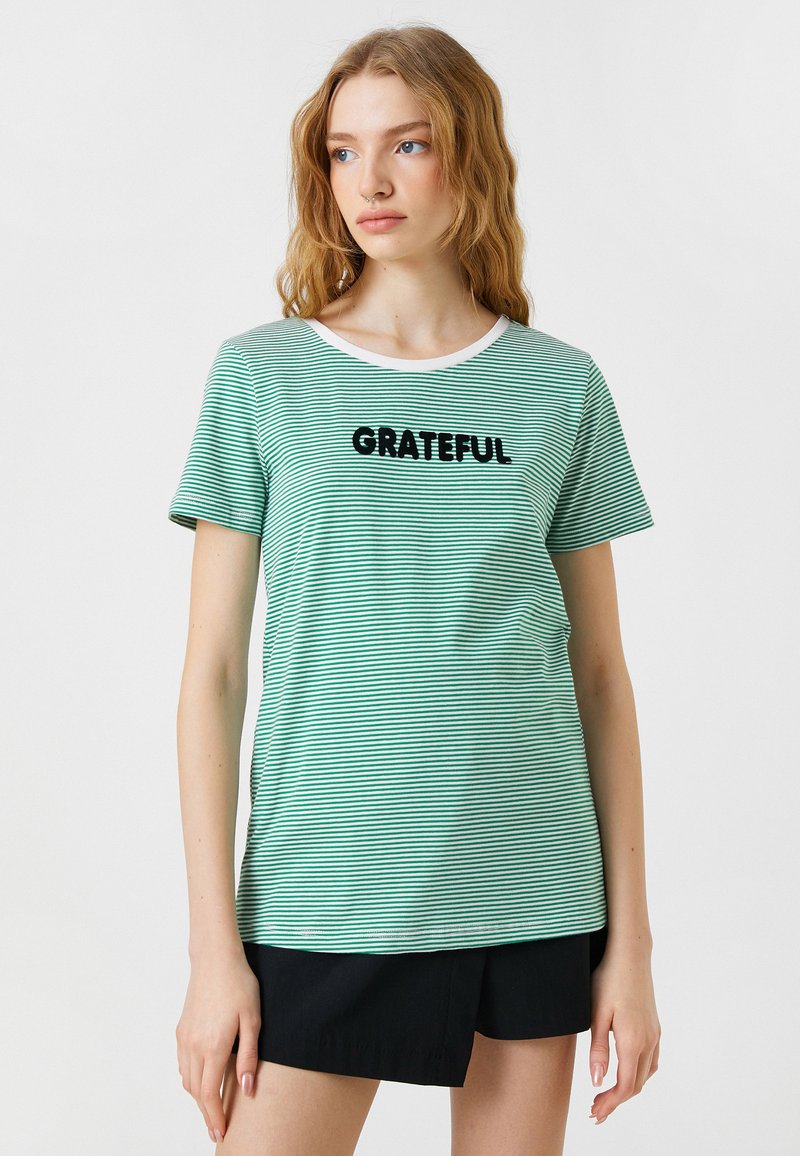 Grøn- og hvidstribet t-shirt med korte ærmer, rund halsudskæring og sort "GRATEFUL" tekst foran. Blødt stof, afslappet pasform.