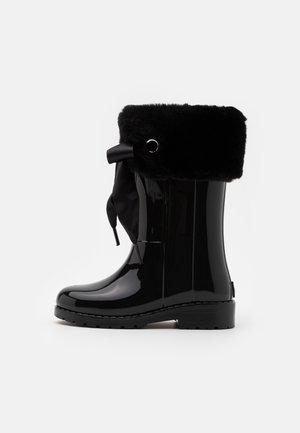 Sorte, blanke gummistøvler med faux fur krave, båndsløjfe og runde øjetilbehør. Gummimateriale, flad sål, design til midten af læggen.