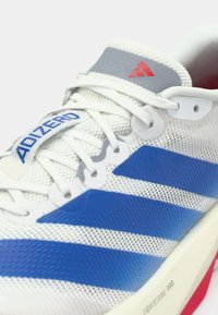 Valge sportjalanõu siniste triipude, võrgukangast ülaosa ja halli kraega. Omab punaseid aksente ja tekstuuriga tallaplaati, millel on kiri „Lightstrike Pro“.