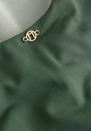 Tkanina w kolorze oliwkowym o gładkiej fakturze, z siateczkowym fragmentem oraz małym, złotym okrągłym zapięciem po dolnej stronie.