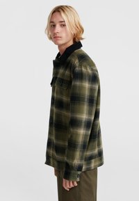 Geruite shirt in donkergroen, zwart en beige, met een corduroy kraag en knoopsluiting, gemaakt van een gestructureerde stof.