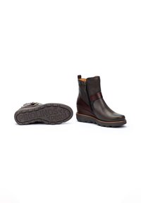 Botas de cuero hasta el tobillo en marrón oscuro, con un zipper lateral, una correa de acento marrón y una suela texturizada con la marca "Pikolinos".