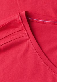 Rood katoenen t-shirtstof met een soepele textuur. Heeft een V-hals ontwerp en contrasterende stiksels rond de halslijn en schoudernaden.