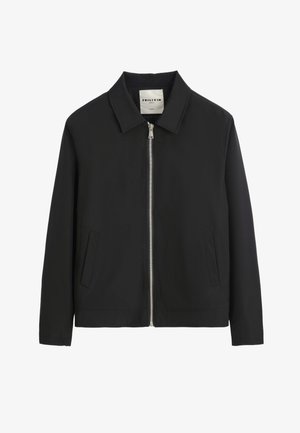 Veste noire en tissu lisse, dotée d'un col montant, d'une fermeture zippée à l'avant et de deux poches latérales avec un ourlet droit.