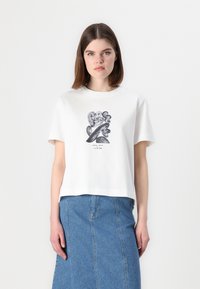Hvit bomulls T-skjorte med rund hals og korte ermer, med et svart grafisk design i midten. Kombinert med et blått denimskjørt.