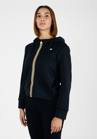 Felpa nera con zip frontale, caratterizzata da una striscia verticale gialla, bianca e blu. Include un cappuccio e polsini a costine.