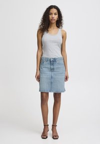 Denim skirt in light blue with a straight cut, front pockets, and belt loops, paired with a fitted grey tank top and black strappy sandals.