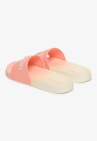 Chanclas de color rosa con un acabado mate suave, tiras anchas con logotipo en relieve y una suela de goma blanca acolchada.