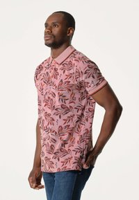 Polo shirt in het roze met meerkleurige bladerenpatronen, voorzien van een kraag, korte mouwen en een slim fit ontwerp.