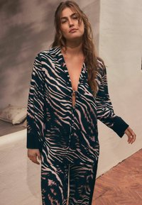 Ensemble de pyjama rayé tigre bleu marin et rose comprenant un haut à boutons avec un détail en trou de serrure et un pantalon ample. Tissu doux au toucher.
