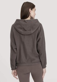 Dunkelgrauer Fleece-Pullover mit Kapuze, der eine weiche Textur, gerippte Säume und lange Ärmel aufweist. Die Rückansicht zeigt Nahtdetails.