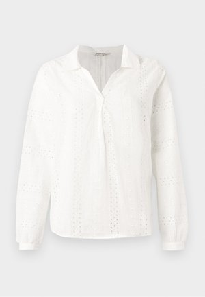 White cotton blouse featuring long sleeves, a V-neck collar, and intricate eyelet embroidery patterns throughout. Classic fit design.