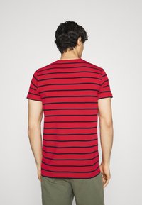 Rødstribet t-shirt med sorte vandrette striber, korte ærmer, rund halsudskæring og en afslappet pasform. Materialet fremstår blødt og åndbart.