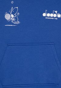 Sudadera azul con un personaje de dibujos animados blanco jugando al tenis. Incluye un bolsillo frontal y el nombre de la marca "diadora" impreso en blanco.