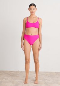 Conjunto de bikini rosa brilhante com parte superior triangular e parte inferior de cintura alta. Tecido suave e elástico, com hardware minimalista e linhas limpas.
