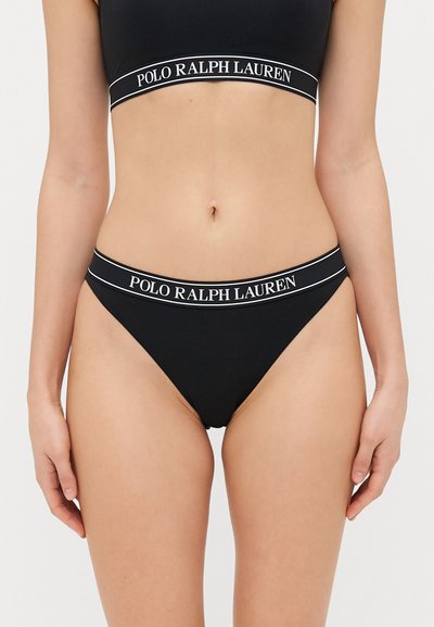 Musta bikinit yhdestä osasta, joissa on ribbileikattu pinta. Yläosassa on paksu nauha, jossa lukee valkoisella "POLO RALPH LAUREN", mikä vastaa bikiniton vyötäröä.