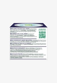Square box with a multicolored lid featuring a light blue gel-cream texture. Text in German and French, QR code on one side for scanning.